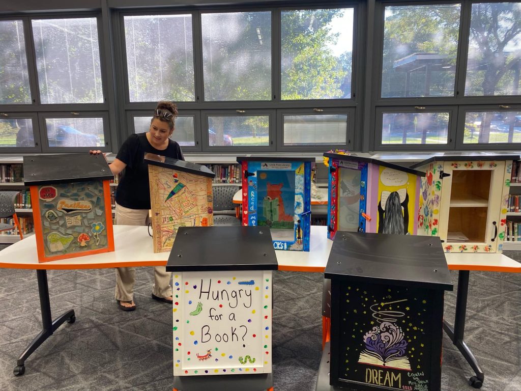 Jennifer Heun standing with the seven Little Free Libraries that will be placed throughout the community during Read Across America Week.  