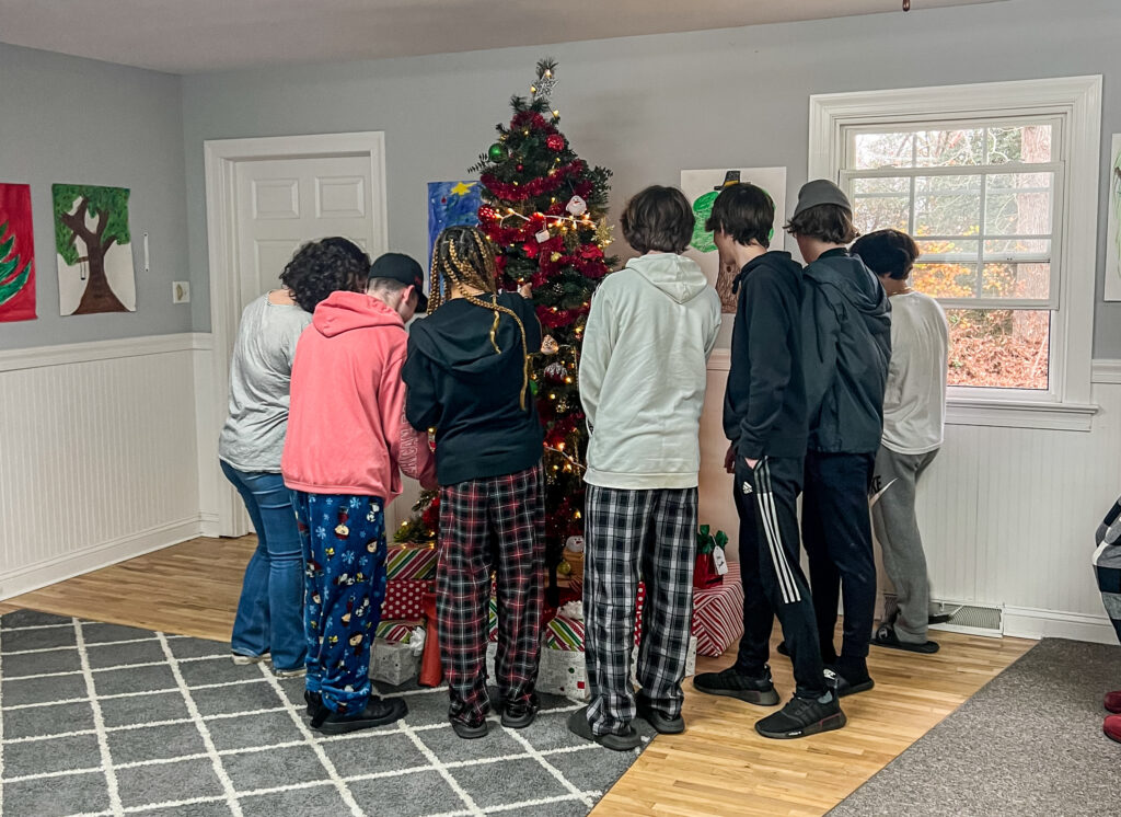 students standing by a christmas tree admiring gifts 
