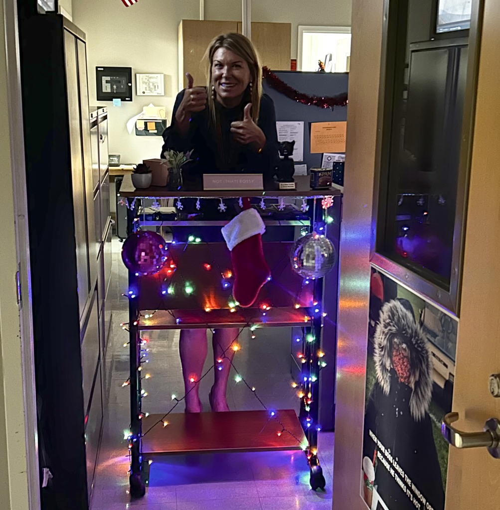 MTHS Principal standing behind desk on wheels with holiday lights