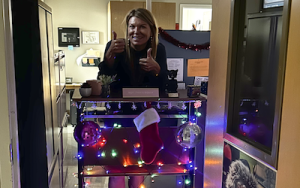 MTHS Principal standing behind desk on wheels with holiday lights