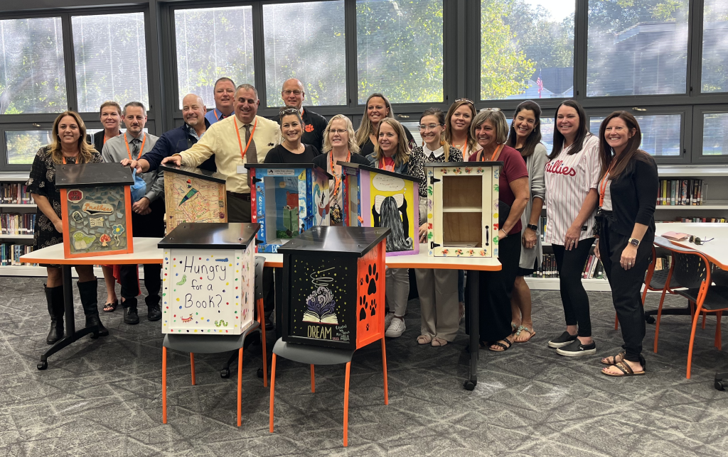 Middle township school district teachers and admins pose of a photo in front of seven miniature libraries decorated and ready to be placed throughout the district. 