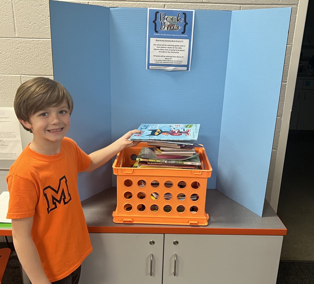 Student placing a book into the school's Read Across America Donation Box w