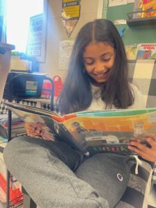 Third grader Josephine Gomes reading The Adventures of Beekle: The Unimaginary Friend. 