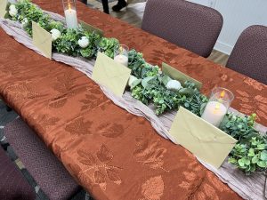 A table set for thanksgiving dinner with cards and decorations.