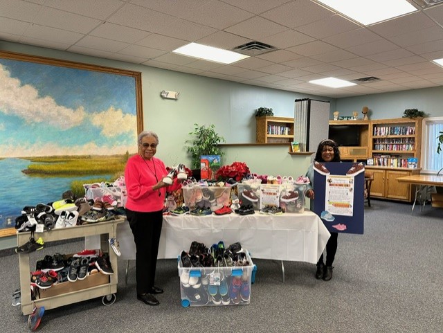 Vice Chair of the Middle Township Senior Center Advisory Board Minnie Callendar and Director Marilyn Miller standing with shoe donations in library at Middle Township Elementary #1. 