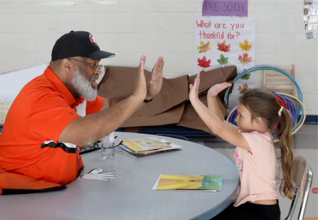 Middle Township school bus driver Herman Cruse reads with Delilah Buckchetsky, 5, at the Middle Township Elementary School, in Cape May Court House, Wednesday, November 27, 2024. Cruse was looking for something to do to pass time in between routes so he started reading to students// Vernon Ogrodnek